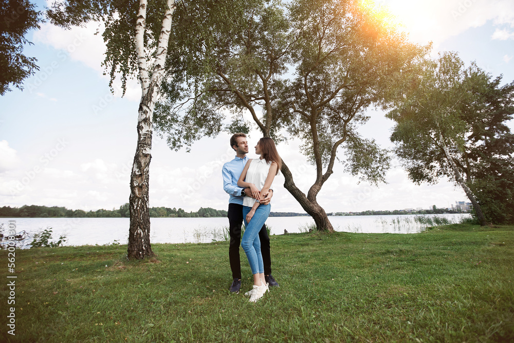couple in love hugs standing on the lawn near the lake . couple in love hugs standing on the lawn near the lake .
