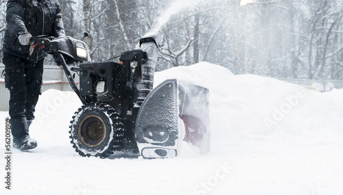 a janitor on a snowplow removes snow in the courtyard of a residential building