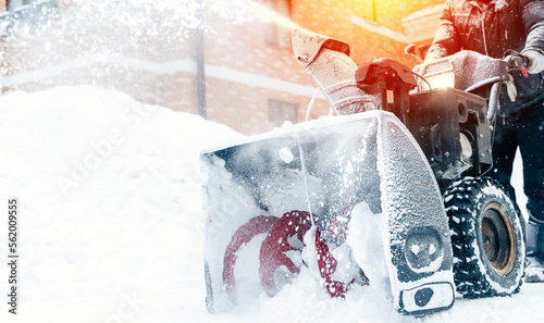 a janitor on a snowplow removes snow in the courtyard of a residential building photo