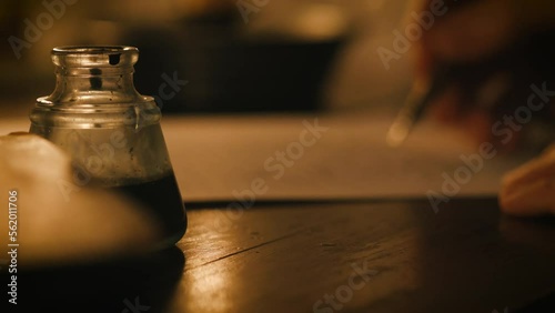 man writing using a dip pen and ink at his desk