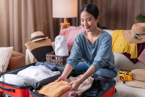 asian young mature adult female woman ready to travel, asian female wear casual cloth arrange packing cloth in suitcase luggage and stuff on the floor in living room for travel after lockdown is over