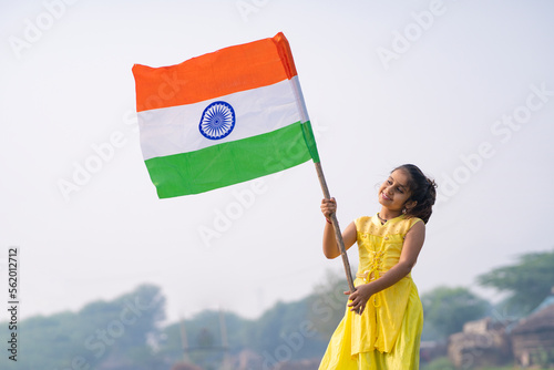 Obraz na plátně Cute indian little girl waving national tricolor flag at agriculture field