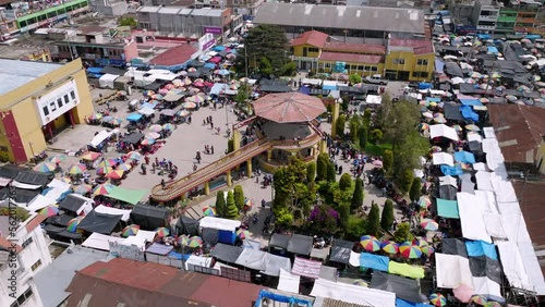 Slowly aerial rotation of the park in the middle of the town square in San Juan Ostuncaclo during the market. photo