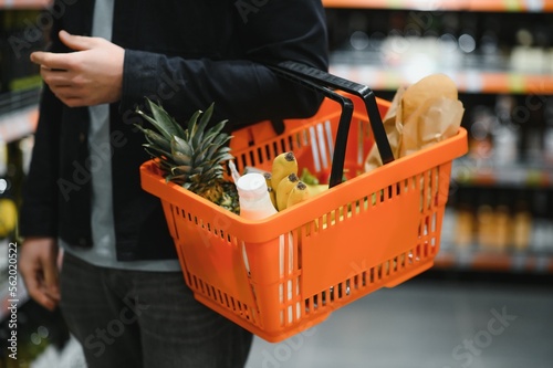 Handsome man buying some healthy food and drink in modern supermarket or grocery store. Lifestyle and consumerism concept. photo