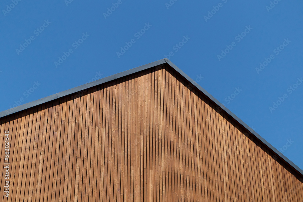 Wooden plank gabled roof on a new modern house against a blue clear sky, copy space.