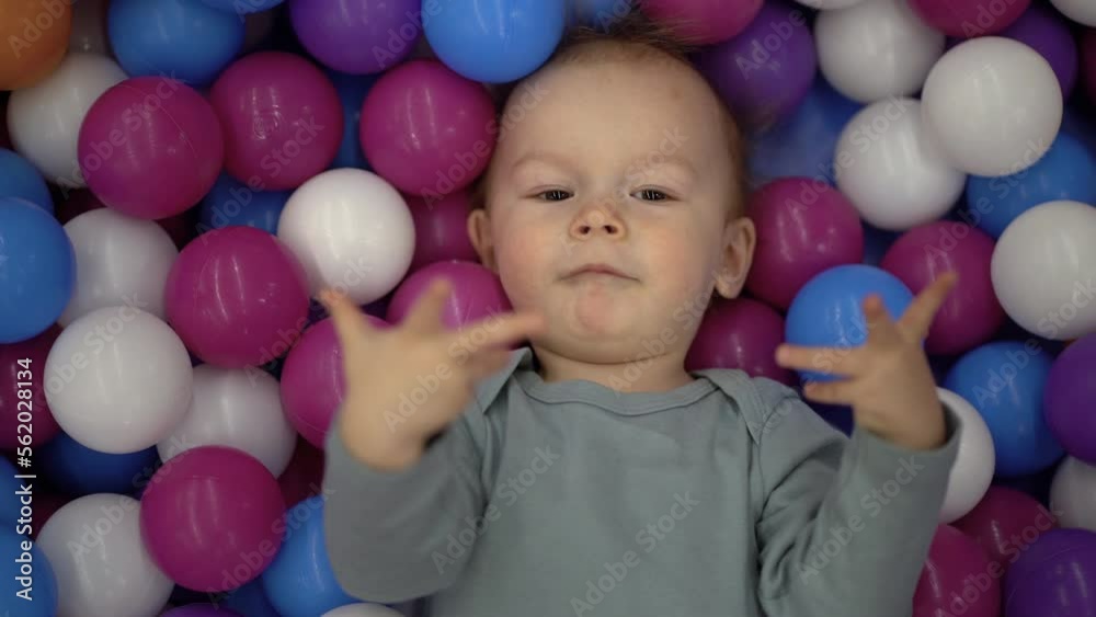 A one-year-old baby lies in a pool with multi-colored plastic balls. A one-year-old baby lies in a pool with multi-colored plastic balls.