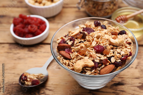 Tasty granola served with nuts and dry fruits on wooden table, closeup