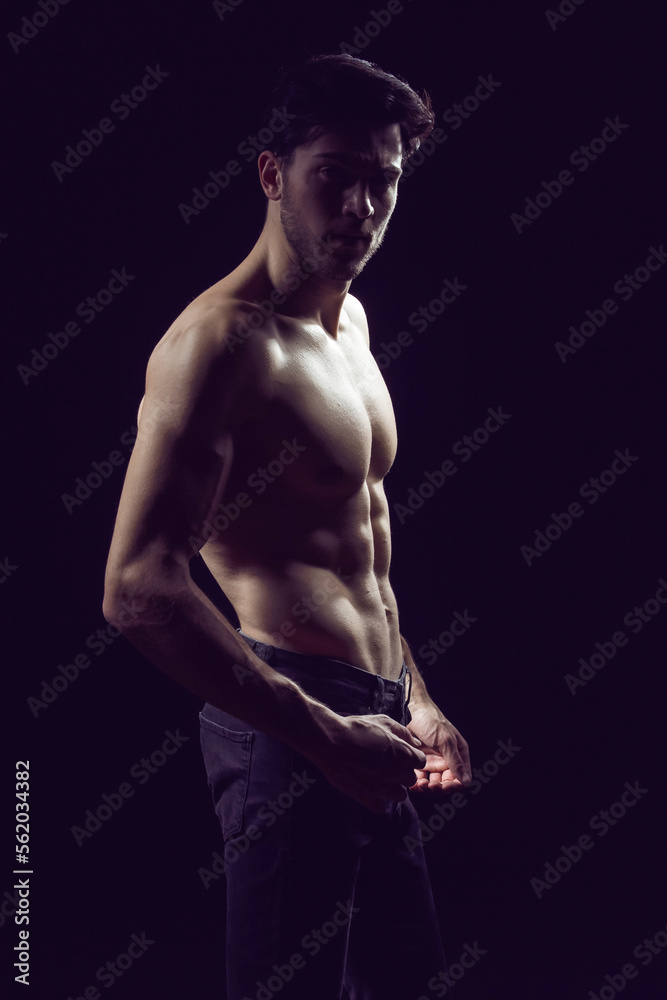 Naklejka premium Natural Portrait of Confident Thinking Caucasian Bodybuilder Athlete Man Posing With Naked Torso Against Dark