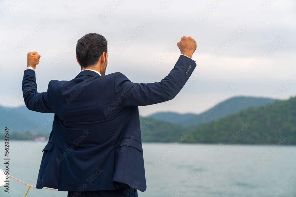 Confident Caucasian businessman raise hand up with shouting celebrating for global business success while travel on luxury private catamaran boat yacht sailing in the ocean on summer holiday vacation Confident Caucasian businessman raise hand up with shouting celebrating for global business success while travel on luxury private catamaran boat yacht sailing in the ocean on summer holiday vacation