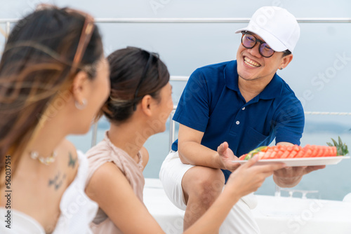 Asian man waiter serving fresh fruit to woman passenger tourist on luxury catamaran boat yacht sailing in the ocean. Attractive girl enjoy outdoor lifestyle travel on summer holiday beach vacation. © CandyRetriever 