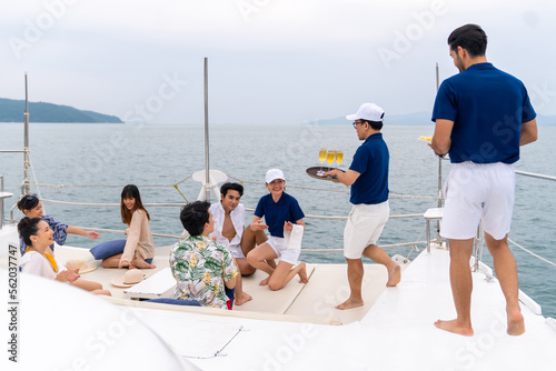 Yacht crew serving fruit and champagne to passenger tourist during celebration party travel on luxury catamaran boat yacht sailing in the ocean on summer vacation. Cruise ship service occupation. © CandyRetriever 