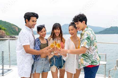 Group of Asian man and woman friends enjoy and fun luxury outdoor lifestyle celebration party drinking champagne together while travel on catamaran boat yacht sailing in the ocean on summer vacation