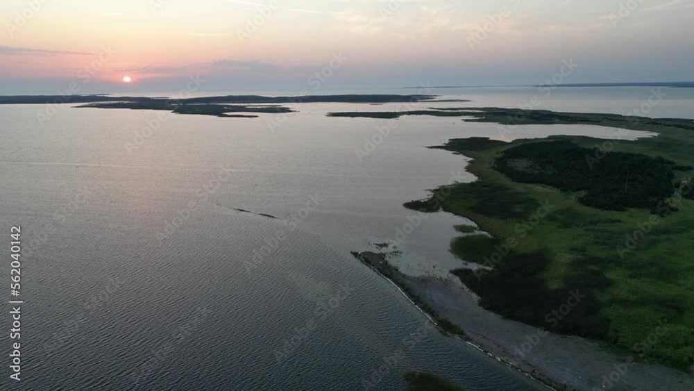 Chain of islands and hiking road underwater. Aerial view flying over chain of beautiful islands with sunset. Sunshine colors. Archipelago in aerial drone shot flying over Estonian islands. Chain of islands and hiking road underwater. Aerial view flying over chain of beautiful islands with sunset. Sunshine colors. Archipelago in aerial drone shot flying over Estonian islands.