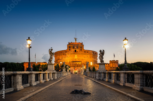 View of the illuminated Mausoleum of Hadrian, known as Castel Sant'Angelo from the Sant'Angelo bridge in blue hour before sunrise.