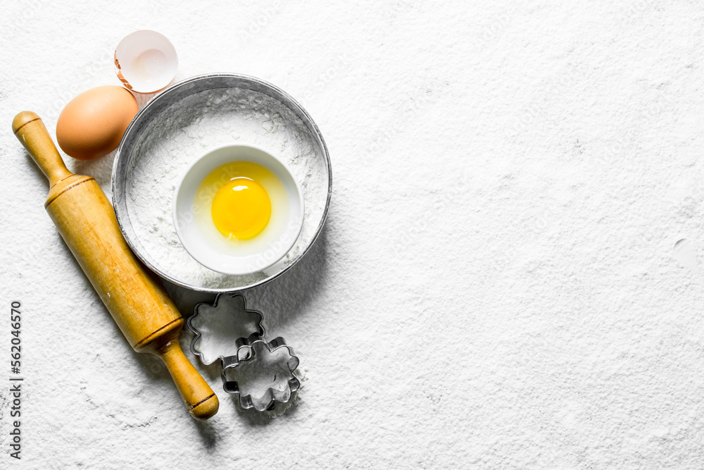 Baking background. Flour with eggs, rolling pin and forms for the dough.