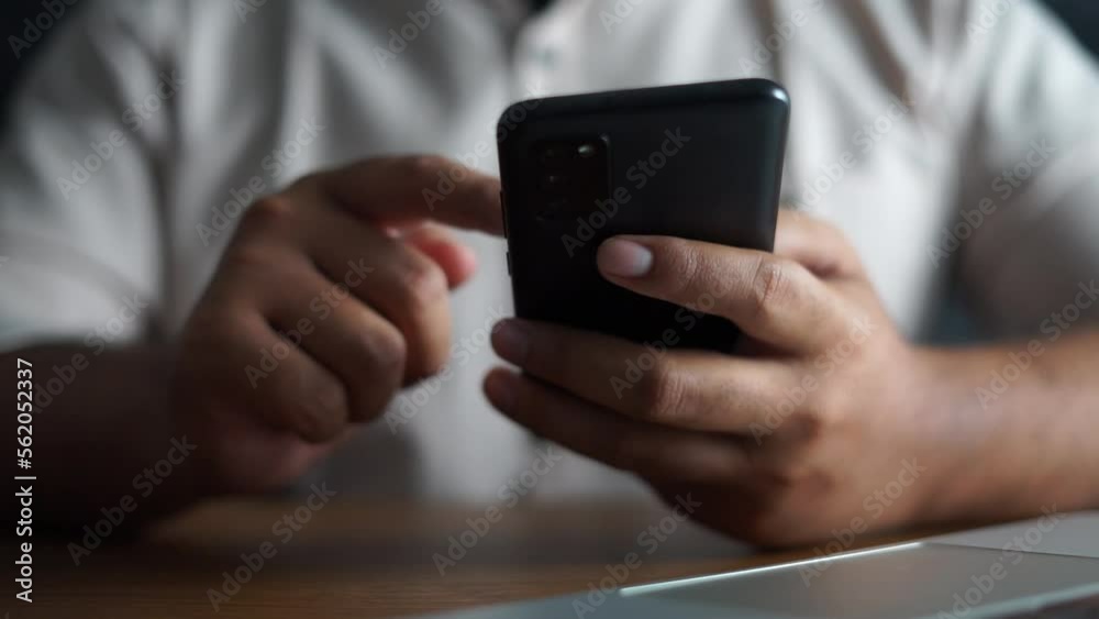 hand scrolling smartphone with laptop on office desk
