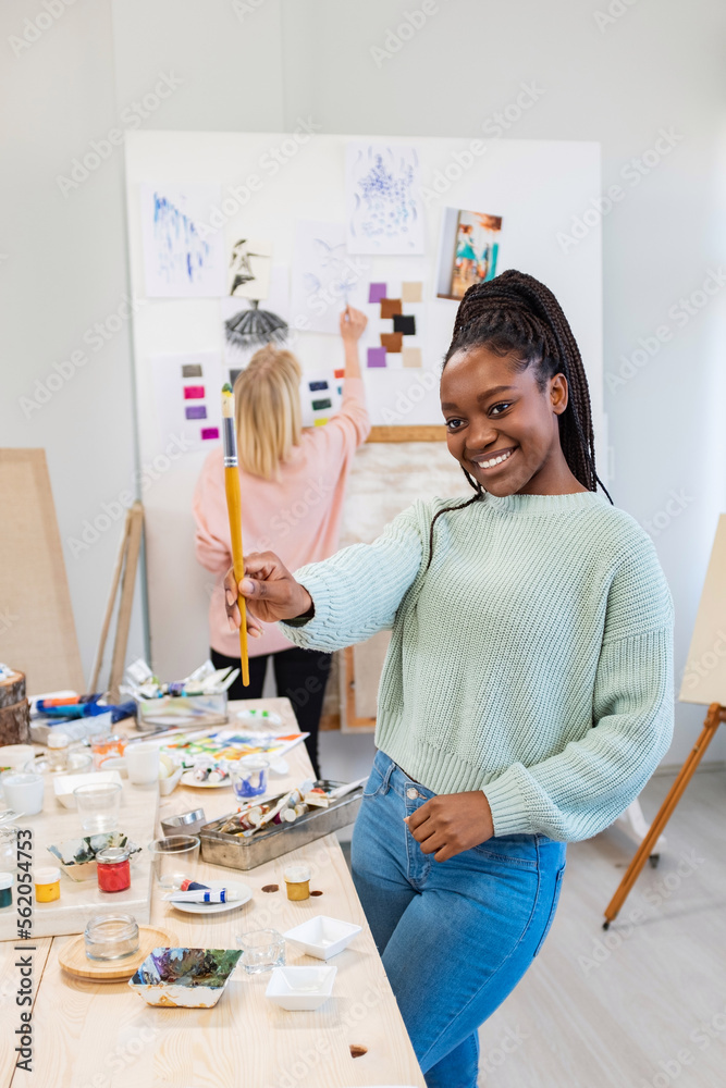 Young female artists are in their painting studio, african artist is ...