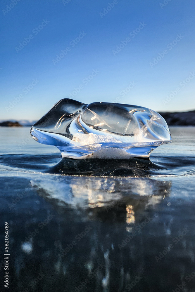 Beautiful ice on Lake Baikal on a clear winter day. Transparent ice block on Lake Baikal. Ice floe and sun on winter Lake Baikal. beautiful ice on a frozen lake on a sunny day. Selective focus.  