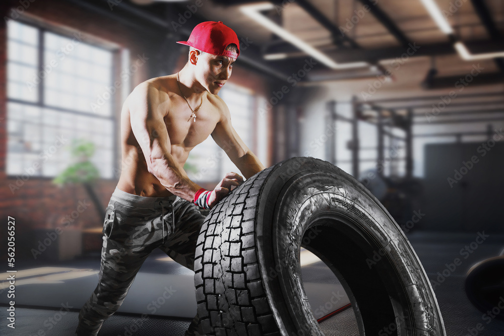 Φωτογραφία Strong asian sportsman with muscular body lifting heavy wheel in gym