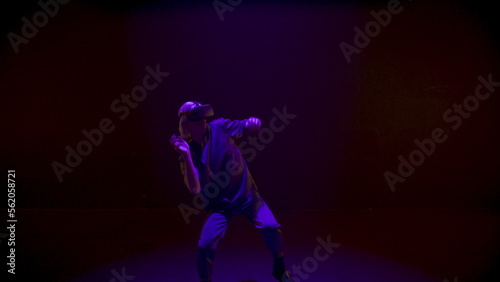 Neon lights gamer dancing in virtual reality headset. Energetic man enjoying