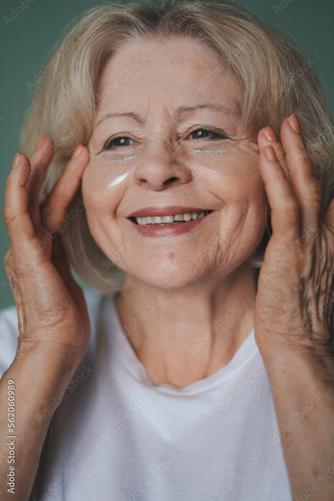 Portrait of smiling woman applying eye patches on her face while wanting to have fresh skin. Beauty treatment. Woman face skin care cosmetic. Body care. Portrait of smiling woman applying eye patches on her face while wanting to have fresh skin. Beauty treatment. Woman face skin care cosmetic. Body care.