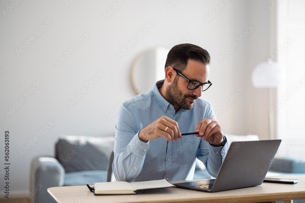 Businessman reading business tasks over the laptop, holding a pencil at the office. Businessman reading business tasks over the laptop, holding a pencil at the office.