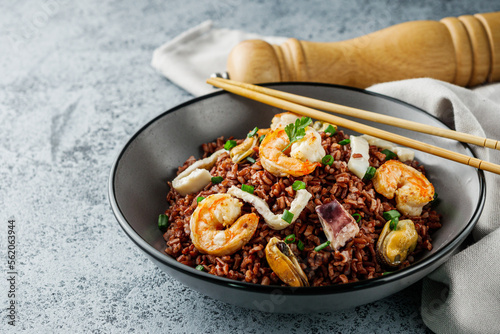 delicious red rice with shrimps and seafood on a gray stone background