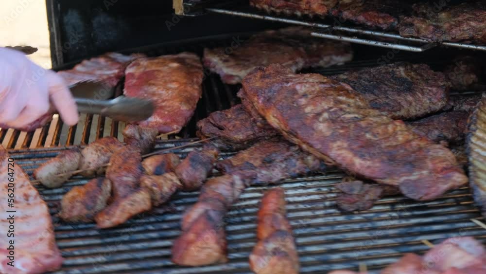 Chef uses tongs turn pork ribs on grill. Street food. Chef uses tongs turn pork ribs on grill. Street food.