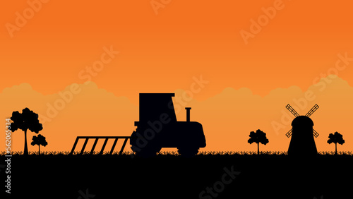 tractor plowing field on rural village landscape.