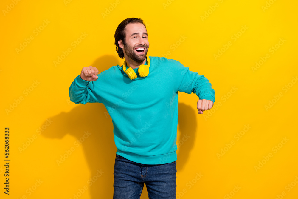 Photo of cheerful positive guy dressed teal outfit earphones having fun isolated yellow color background Photo of cheerful positive guy dressed teal outfit earphones having fun isolated yellow color background
