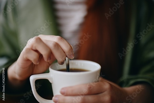 Woman in cafe stirring sugar in white coffee mug  autumn vibe and warm content for social media  blogger