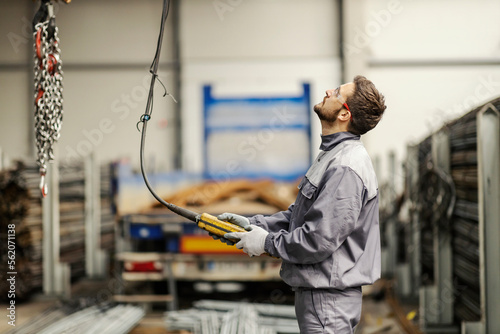 Fotografija A metallurgy worker is maneuvering crane in facility.
