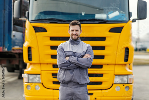 Portrait of a confident truck driver smiling at the camera while standing outdoors in front of the lorry. photo