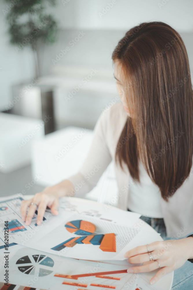 Businesswoman looking at documents, graphs, earnings, business on table in office Businesswoman looking at documents, graphs, earnings, business on table in office