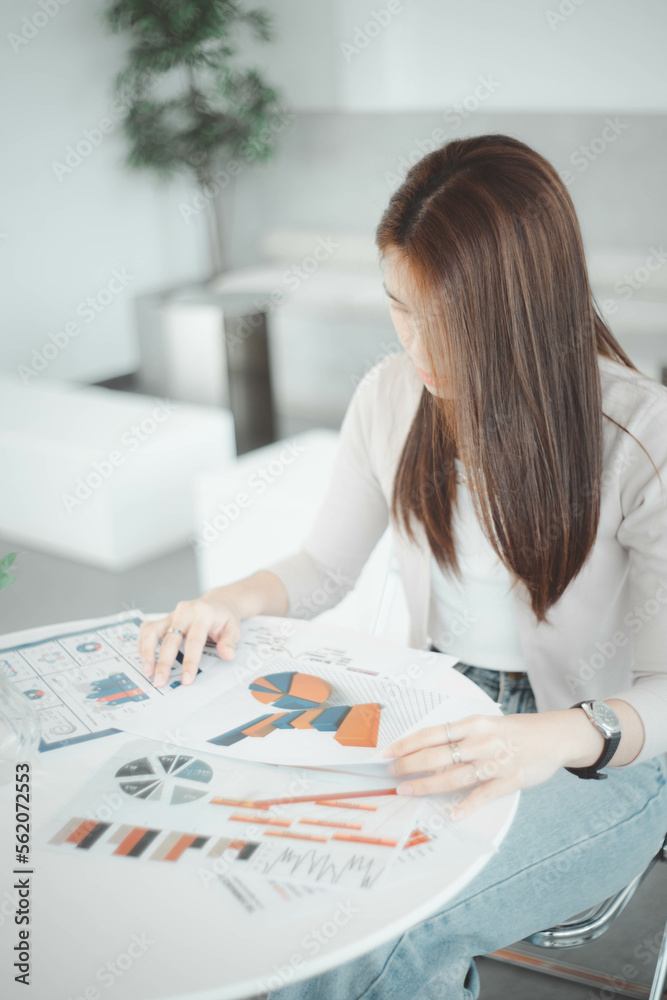 Businesswoman looking at documents, graphs, earnings, business on table in office Businesswoman looking at documents, graphs, earnings, business on table in office