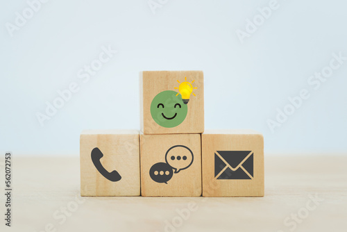 For service mind, consultant, FAQ concept. green smiling face with brighten lightbulb and contact us icon on wooden cube block
