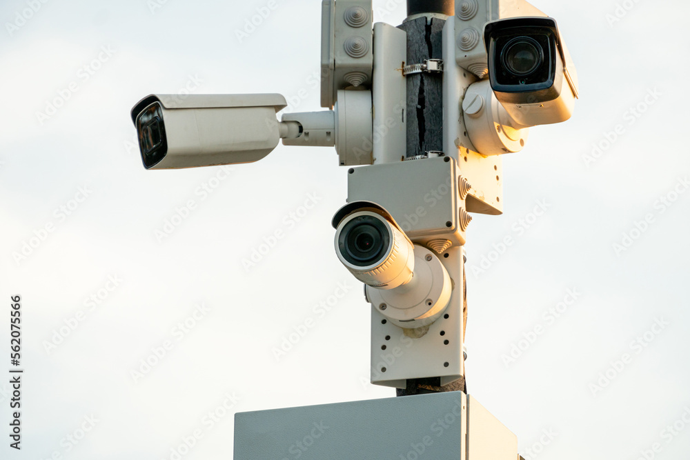 CCTV cameras in a protective white case on a lamppost. Outdoor video surveillance camera installed on the streets of the city for the safety of your property and family. CCTV cameras in a protective white case on a lamppost. Outdoor video surveillance camera installed on the streets of the city for the safety of your property and family.