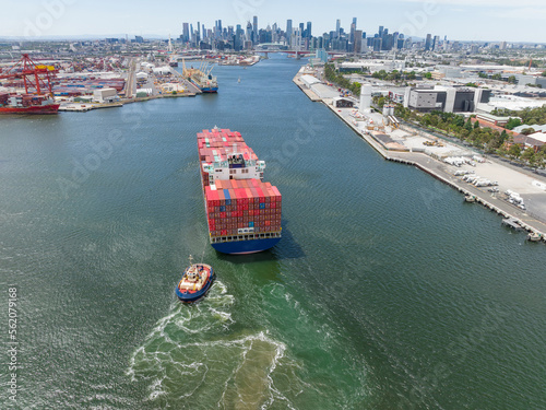 Aerial view of a tugboat moving a large cargo ship up a river