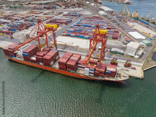 Aerial view of a large cargo ship getting loaded with containers by cranes at a port photo