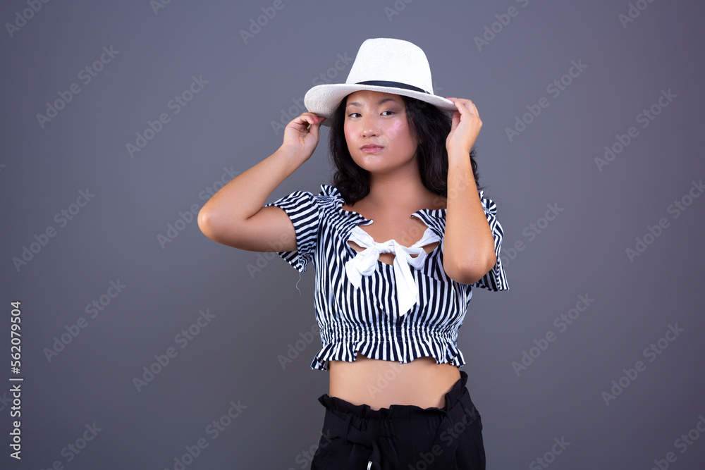 young ethnic asian woman posing with white hat isolated from background young ethnic asian woman posing with white hat isolated from background