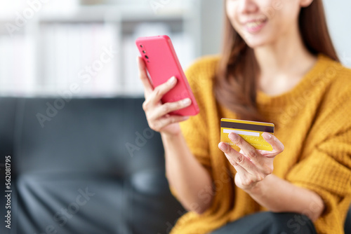Young Asian woman is using credit card to make online purchases on mobile phone, online shopping.