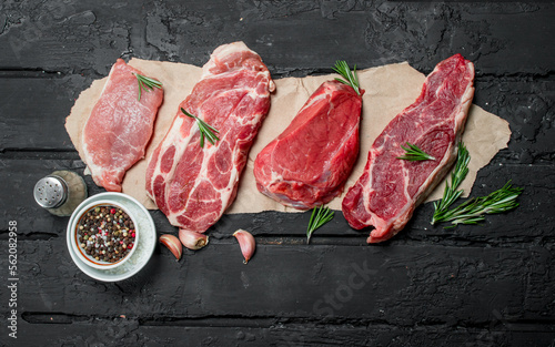 Foto Raw meat. Pork and beef steaks with spices and herbs.