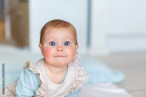 Baby girl with closed lip funny expression leaning forwards photo