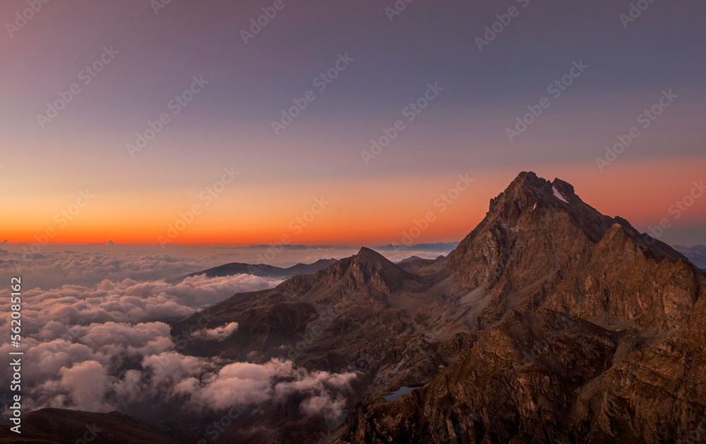 Monviso (3841 m), a mountain in the western Alps, stands out in the intense colors of dawn while the clouds downstream envelop it. Piedmont, Italy, Monviso natural Park.