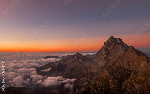 Monviso (3841 m), a mountain in the western Alps, stands out in the intense colors of dawn while the clouds downstream envelop it. Piedmont, Italy, Monviso natural Park.