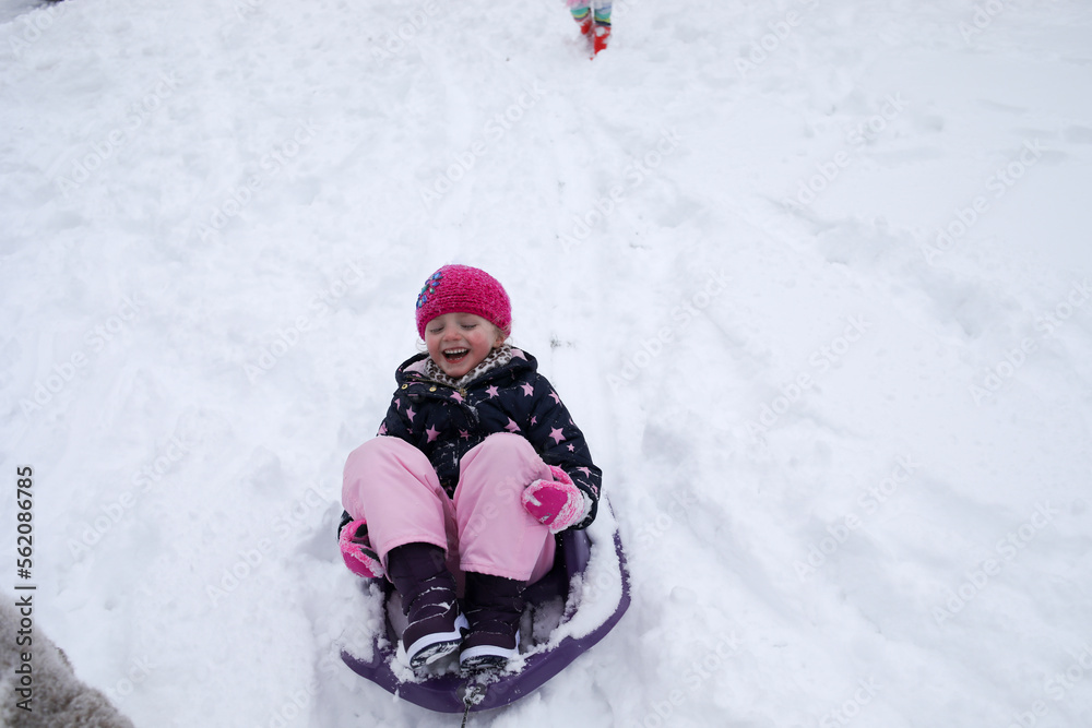 High angle view of cheerful girl sitting on sled during winter High angle view of cheerful girl sitting on sled during winter