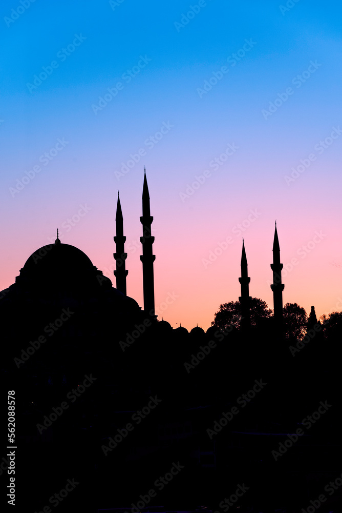 Domes and minarets in silhouette of a Turkish Mosque at sunset on the Istanbul skyline, Turkey.
