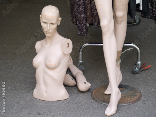 Mannequins awaiting assembly in a clothes stand in an outdoor market photo