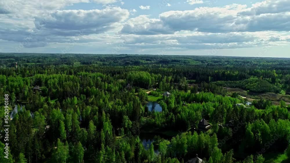 Aerial backwards shot of green forest landscape with lake and apartments in park during sunny day Aerial backwards shot of green forest landscape with lake and apartments in park during sunny day