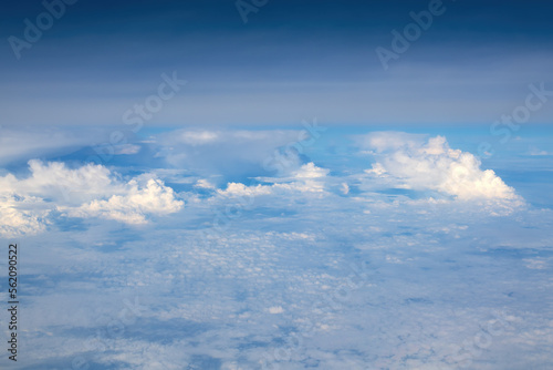 White cumulus clouds seen from the passenger airplane on sunny summer day, aerial view